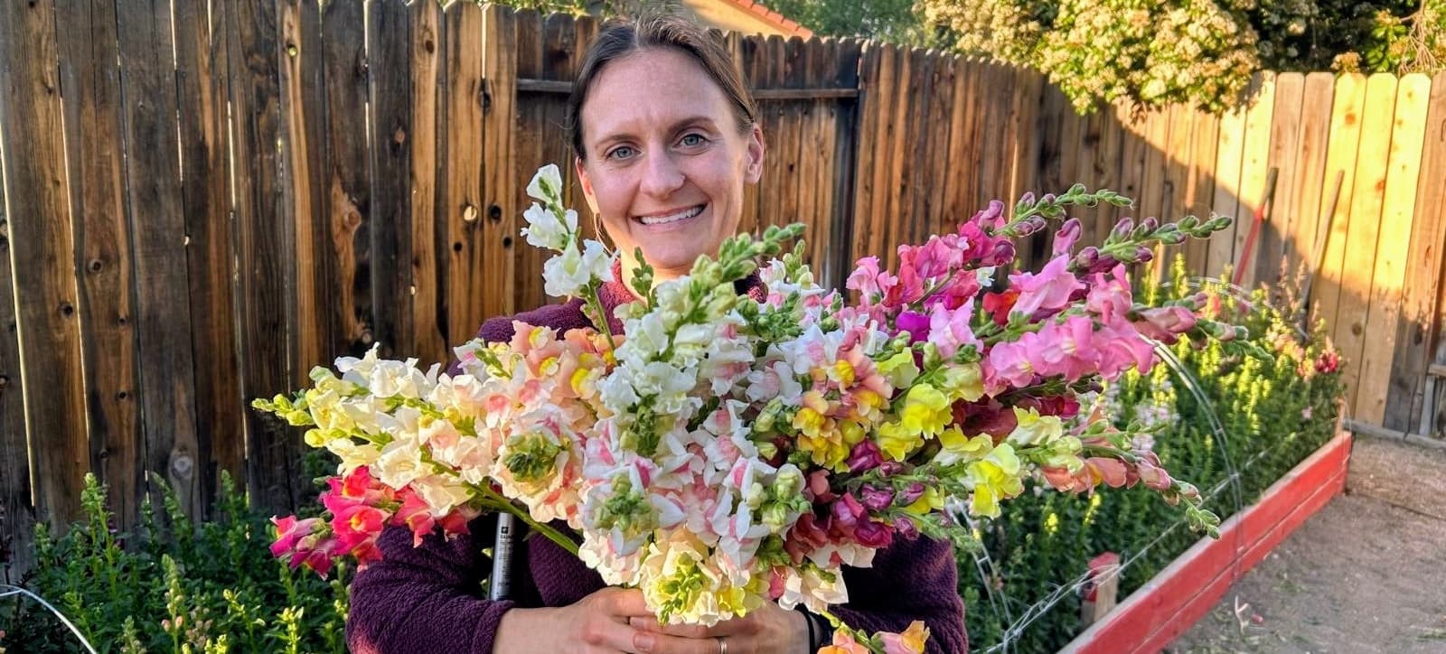 Grace in the garden at Grace's Flower Farm, holding an armful of snapdragons